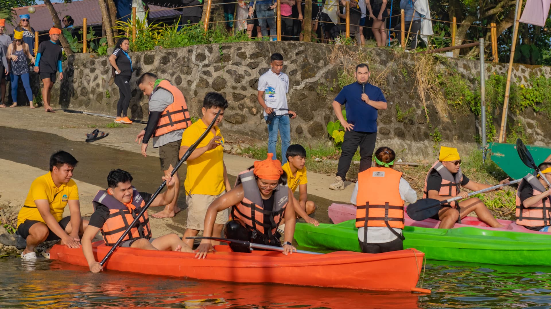 Teams launching colorful kayaks at the shore
